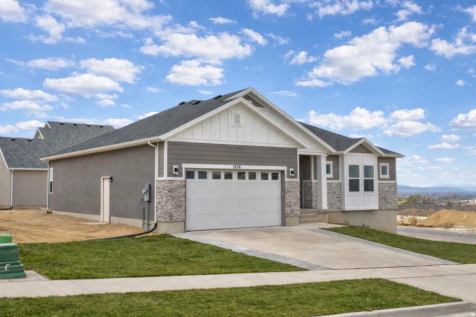 Craftsman-style home with stone siding, board and batten siding, driveway, and an attached garage