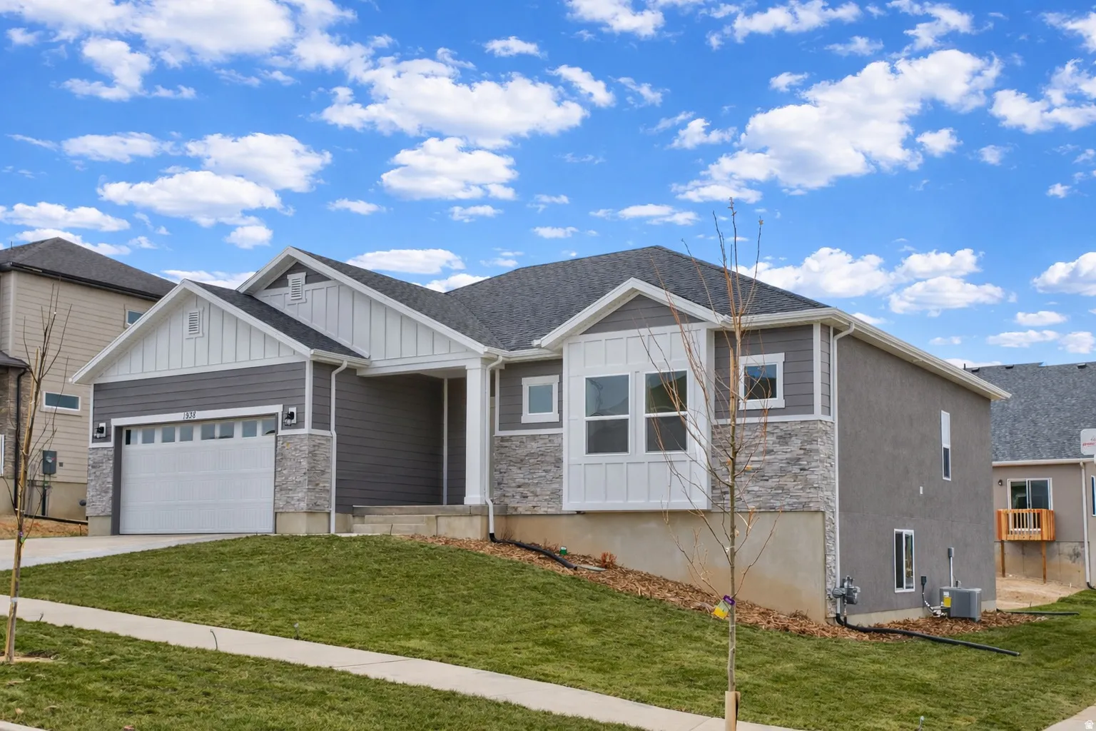 Craftsman house with board and batten siding, a front lawn, a garage, and stone siding