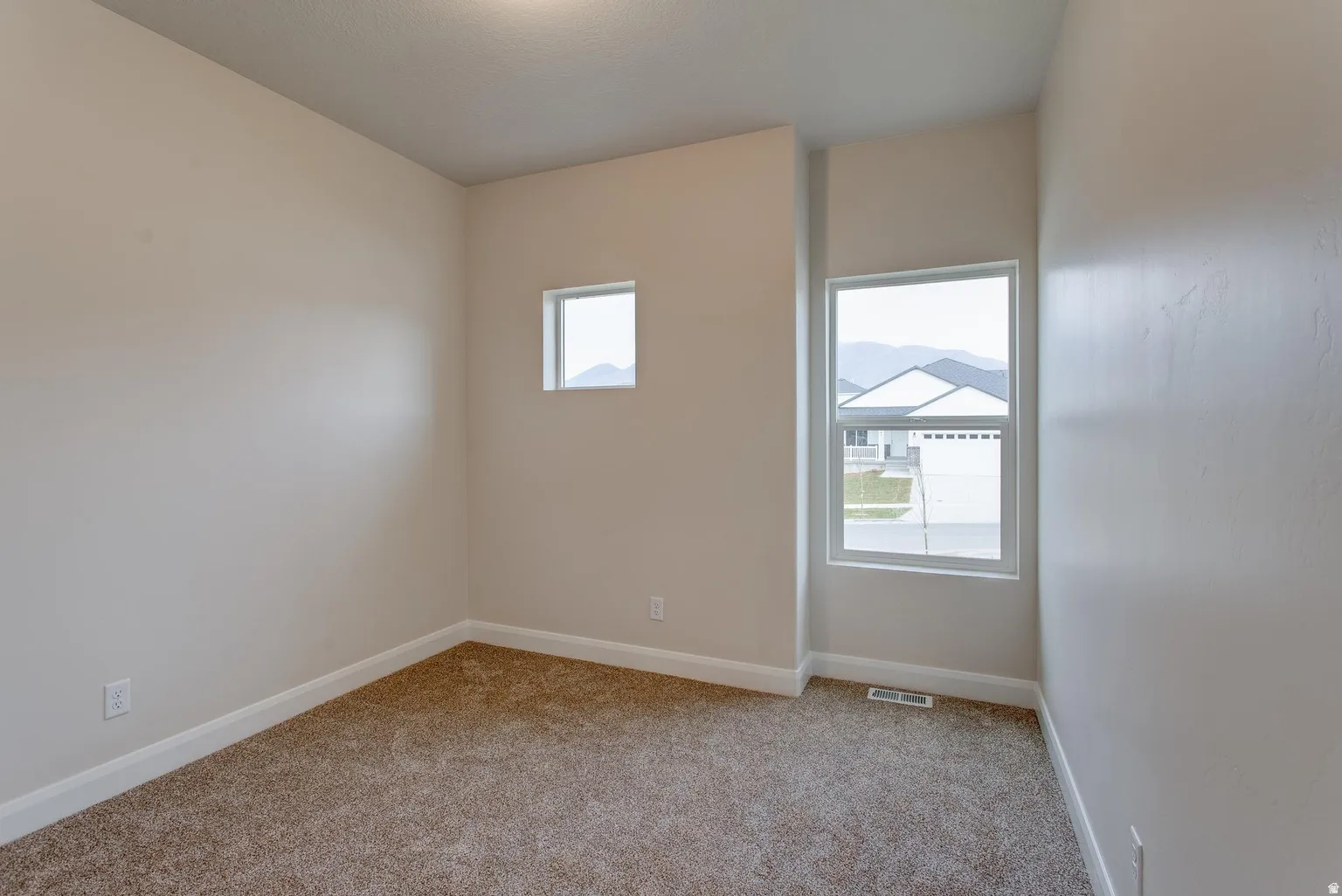 Empty room featuring baseboards and light colored carpet