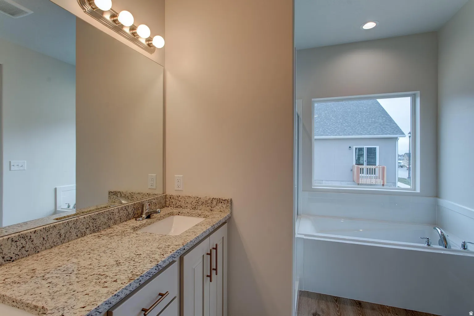 Full bath with vanity, a garden tub, dark wood finished floors, and recessed lighting