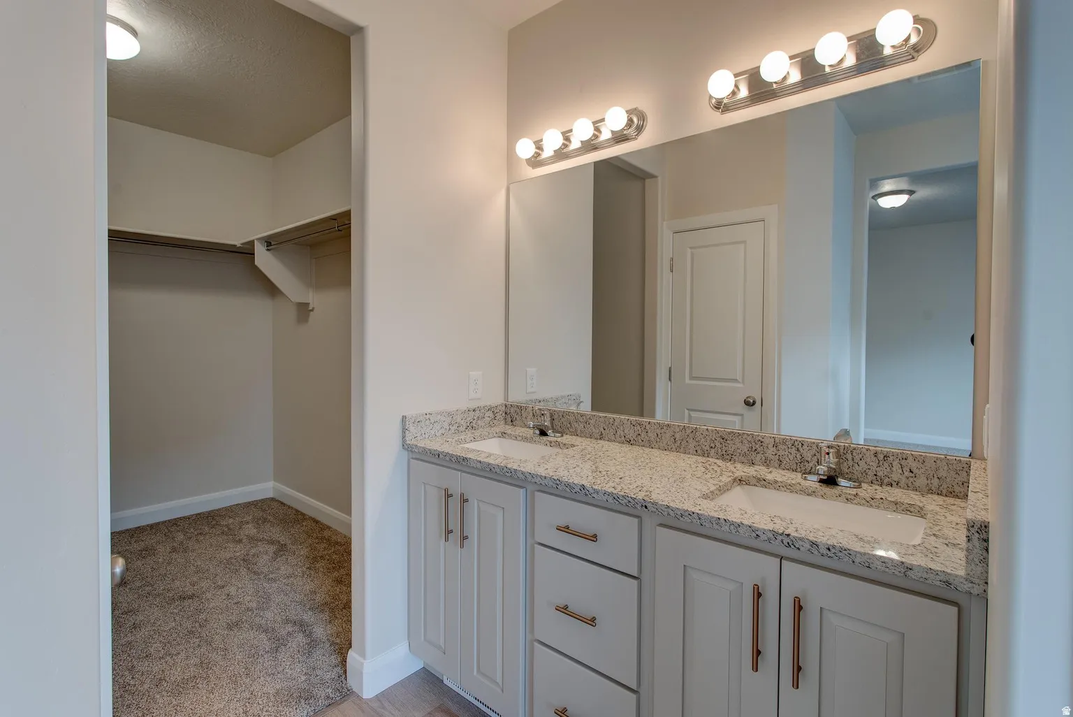 Full bath featuring double vanity, a spacious closet, and a textured ceiling
