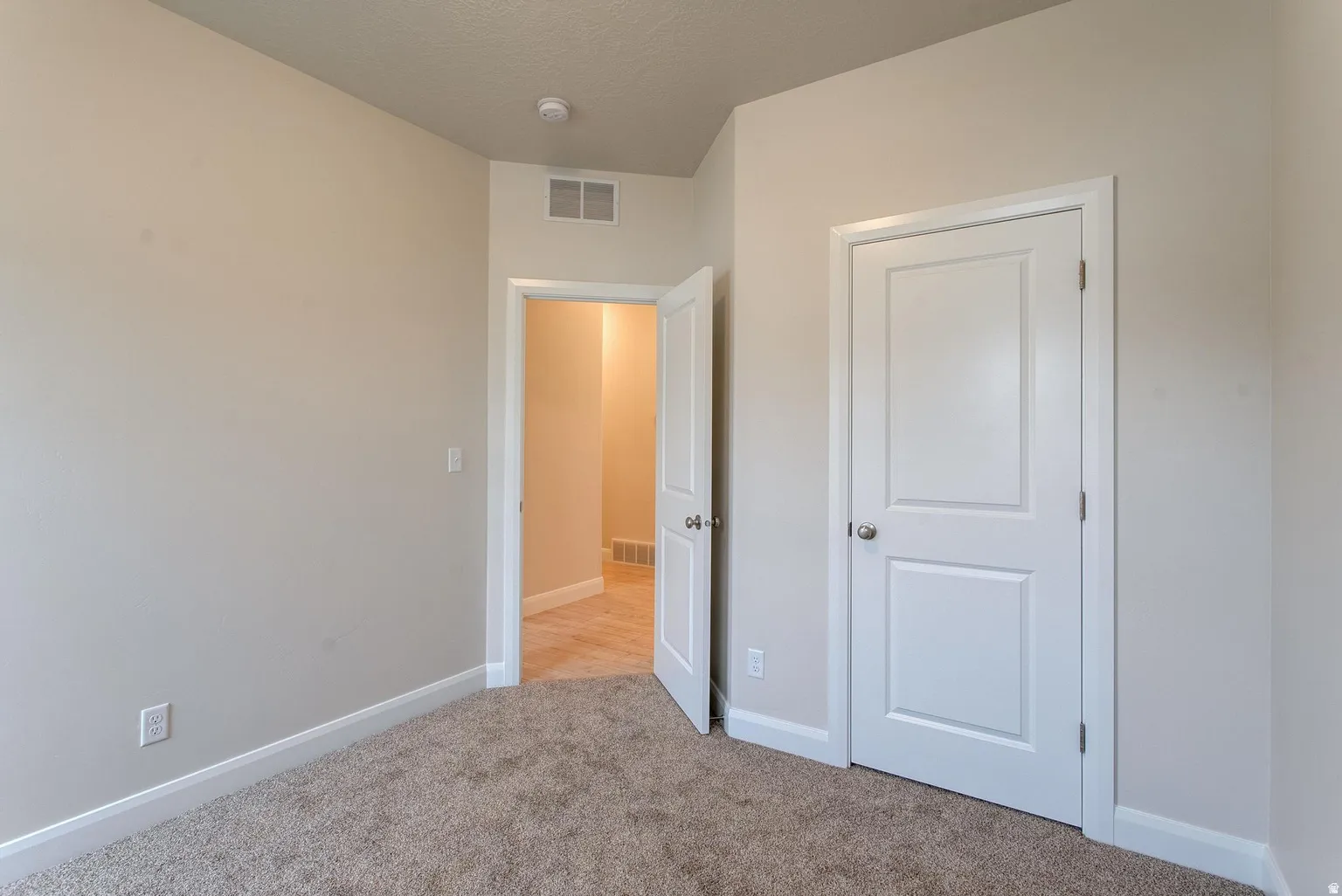 Unfurnished bedroom with baseboards and light carpet