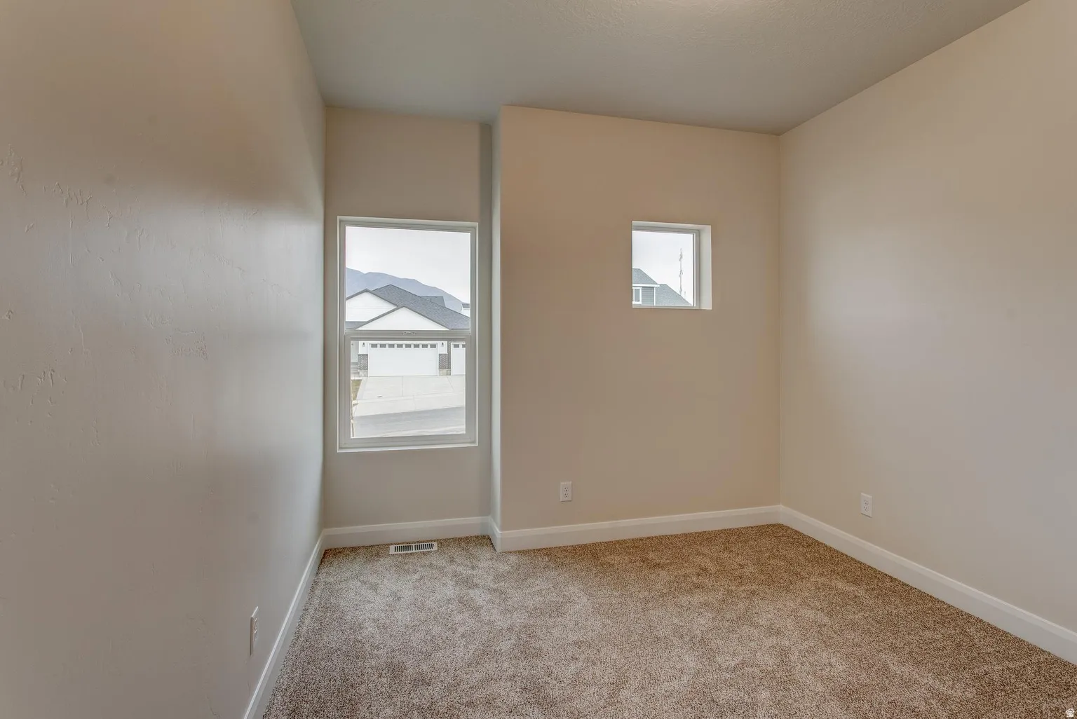 Spare room featuring light colored carpet and baseboards
