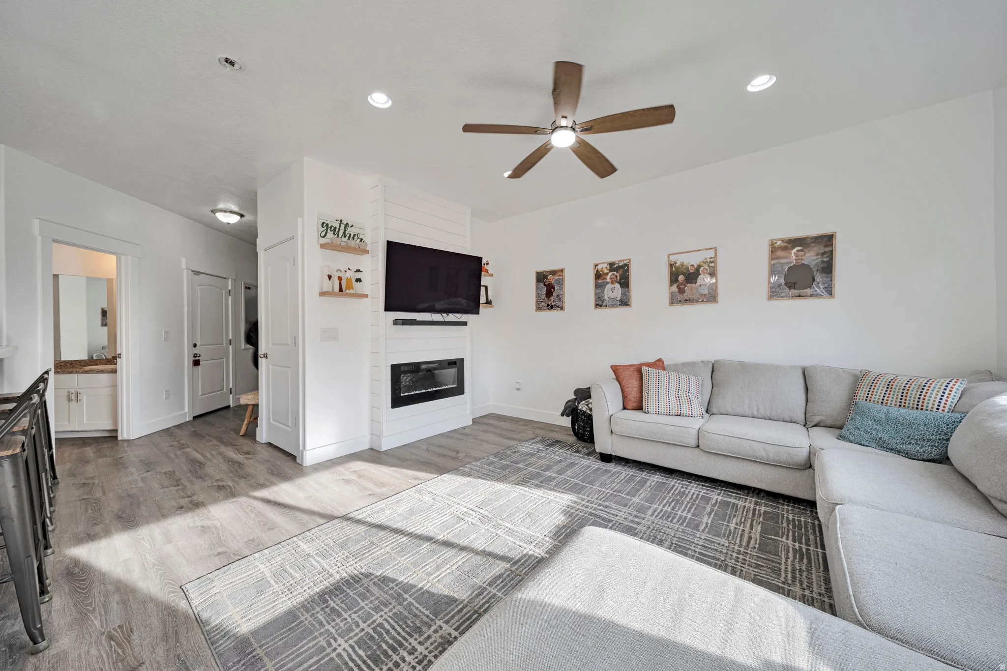 Living area featuring light wood-type flooring, a fireplace, ceiling fan, and recessed lighting