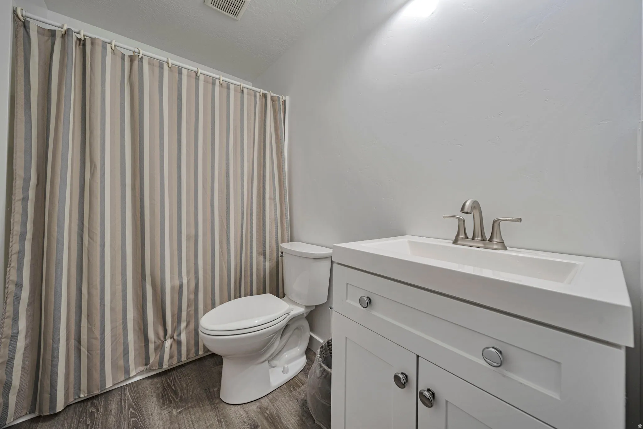 Bathroom featuring vanity, dark wood finished floors, and a textured ceiling