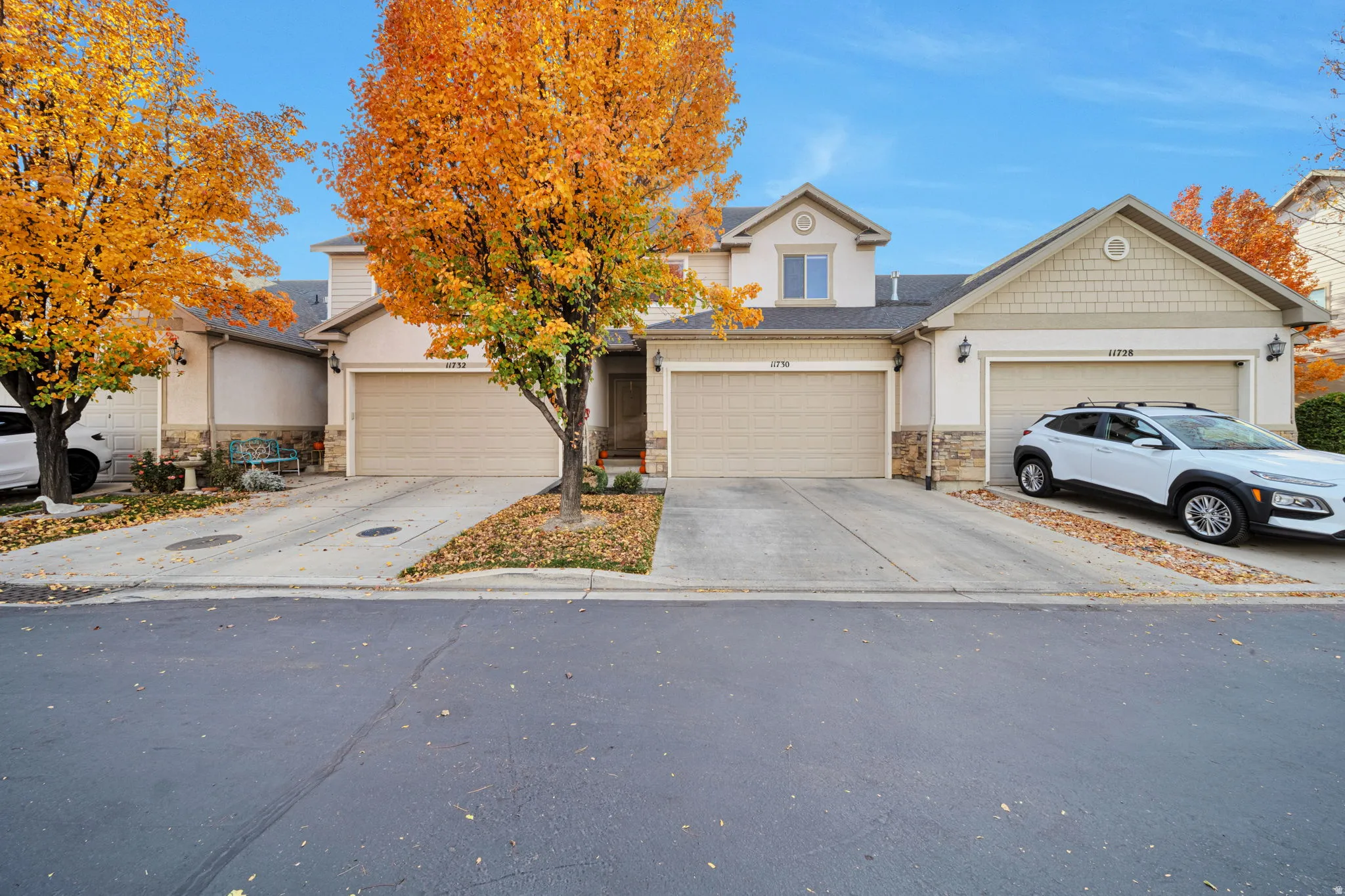 View of front of property with a garage, driveway, stone siding, and roof mounted solar panels