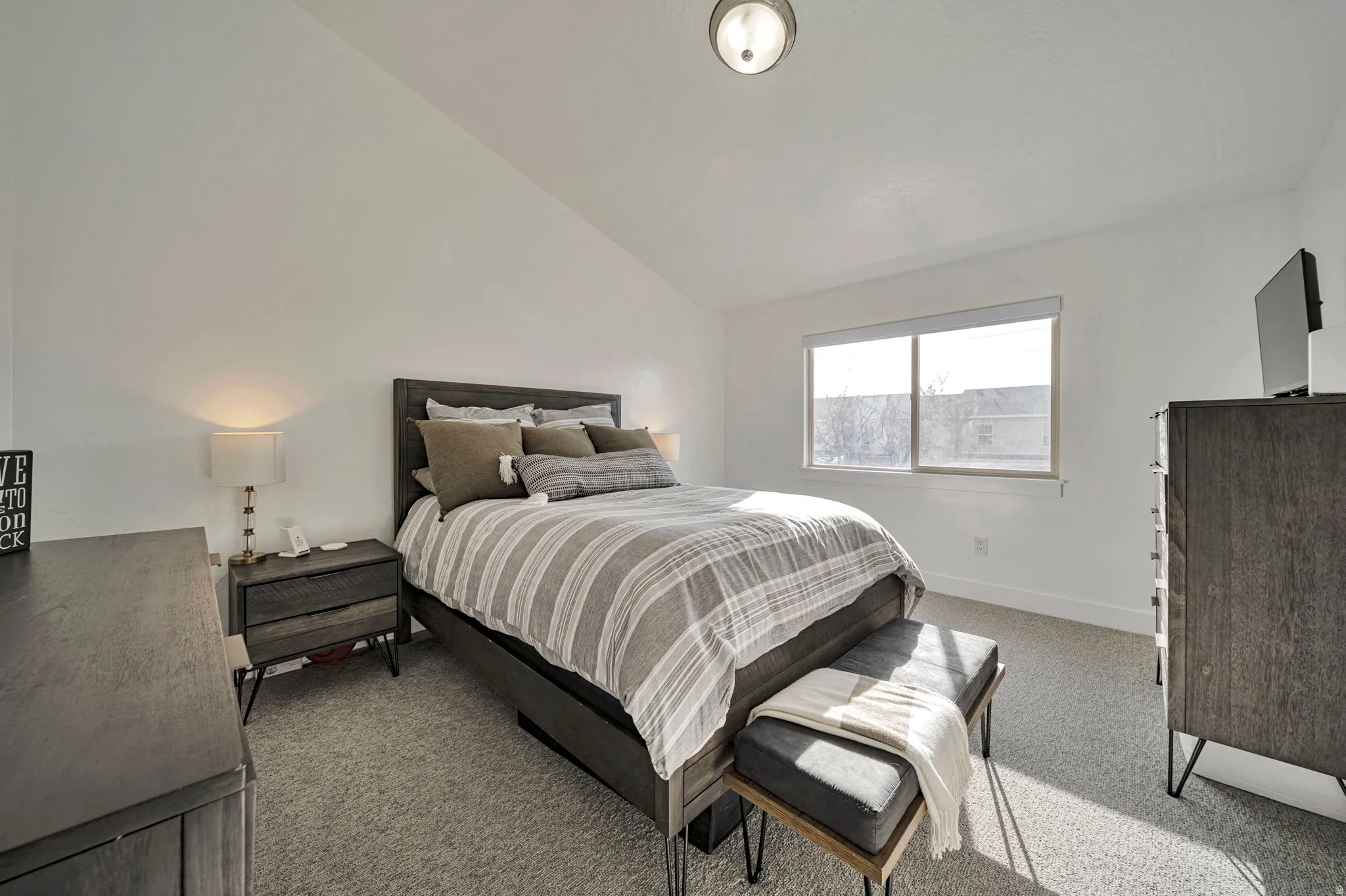 Bedroom featuring lofted ceiling and light carpet