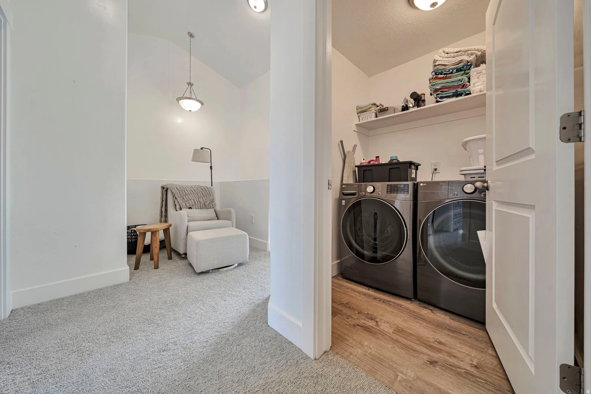 Laundry area featuring vaulted ceiling, washer and clothes dryer, and light carpet
