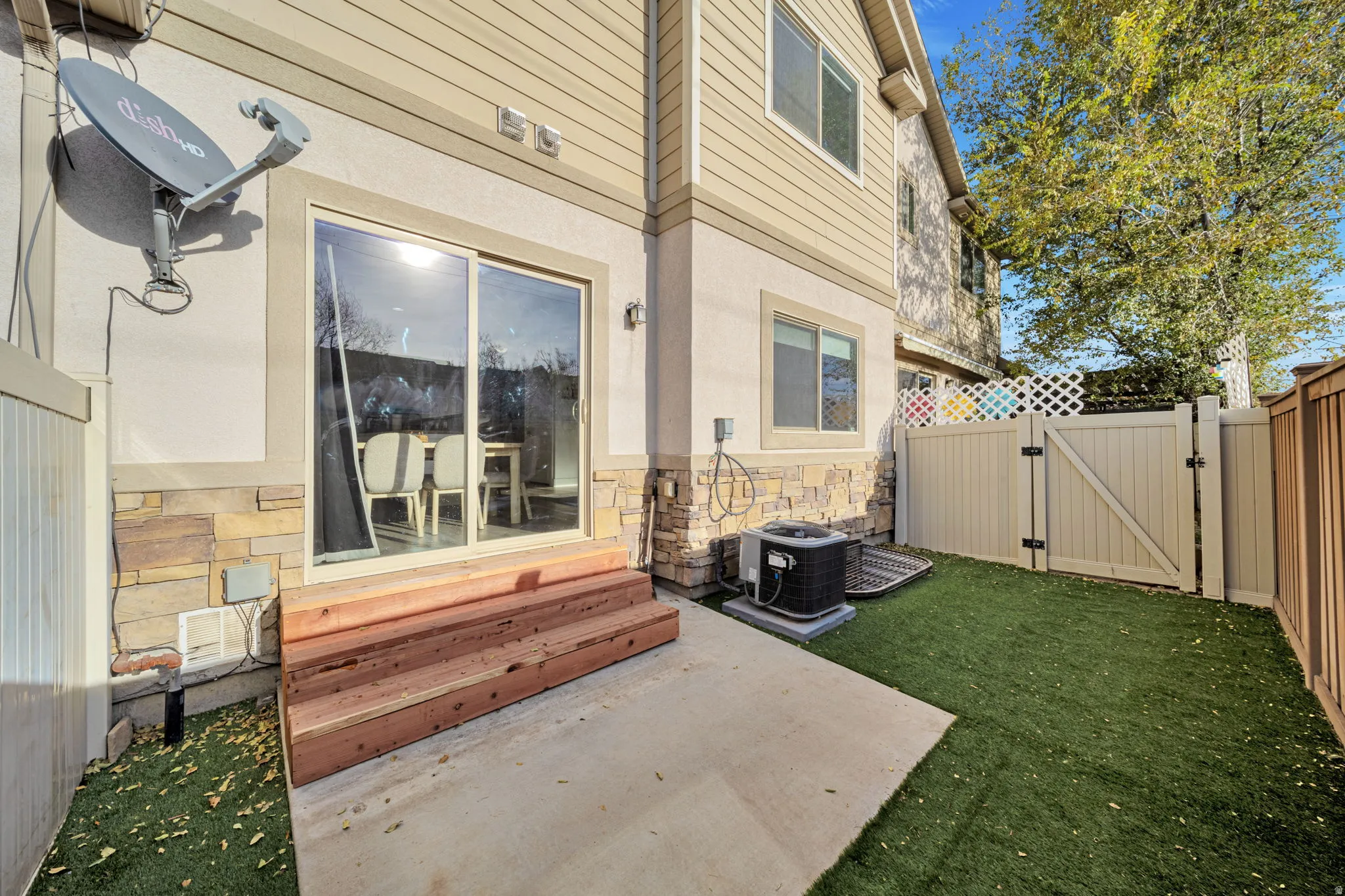 View of exterior entry featuring a gate, a patio area, stone siding, and stucco siding