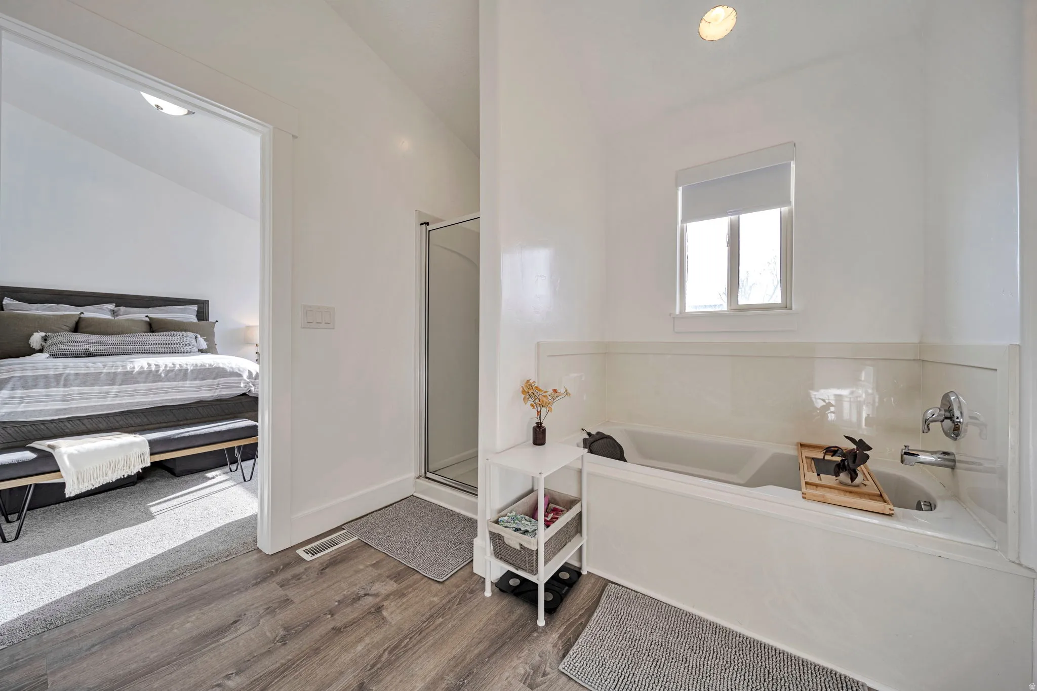 Ensuite bathroom with a shower stall, a bath, and wood finished floors
