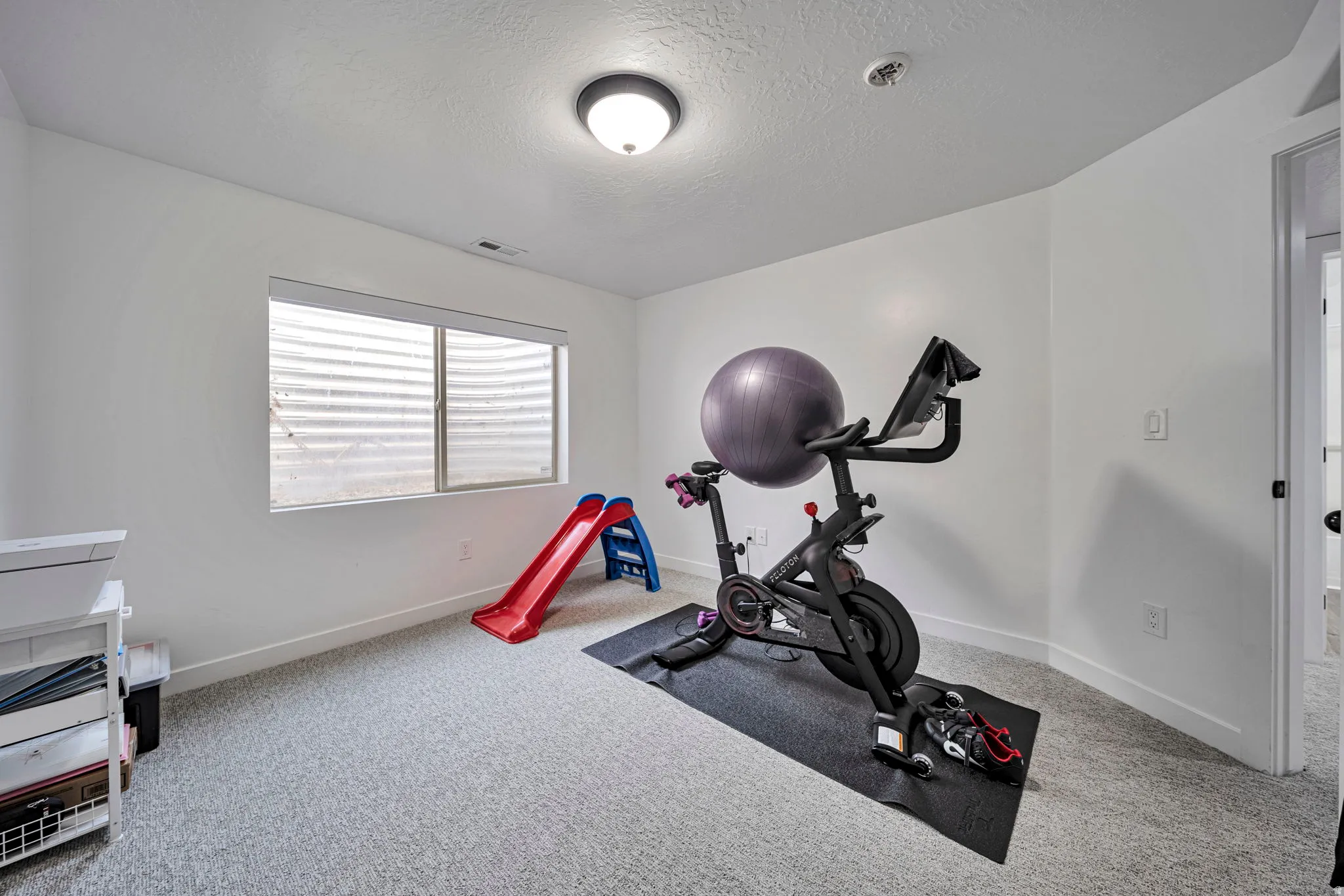 Workout area with a textured ceiling and light colored carpet