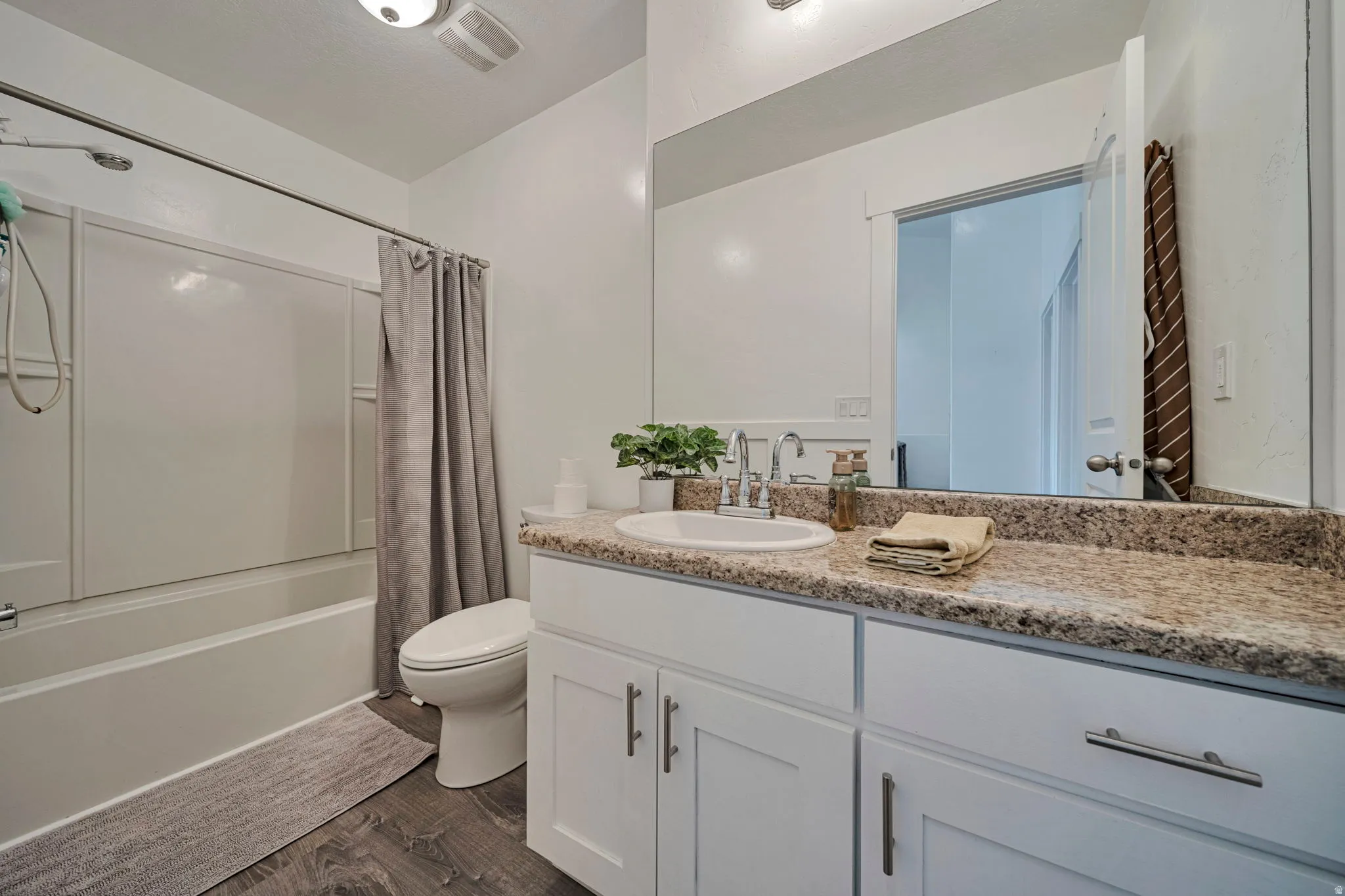 Bathroom with vanity, dark wood-type flooring, and shower / bathtub combination with curtain