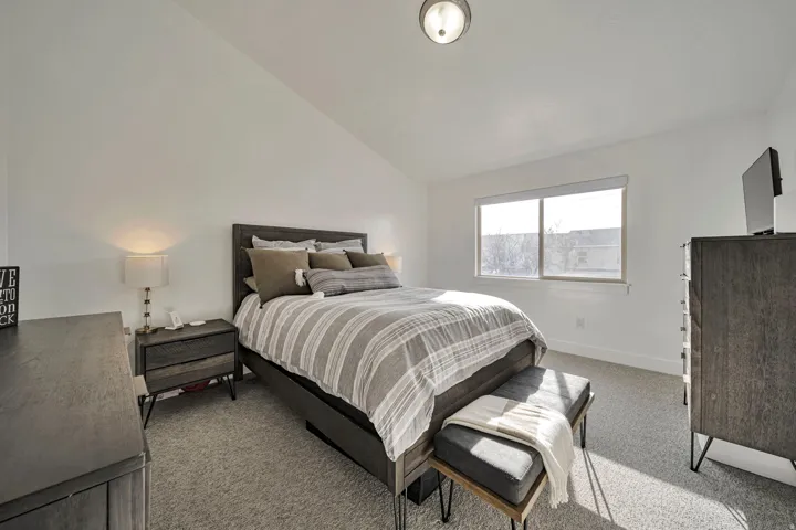 Bedroom featuring lofted ceiling and light carpet