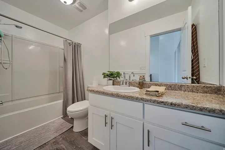 Bathroom with vanity, dark wood-type flooring, and shower / bathtub combination with curtain