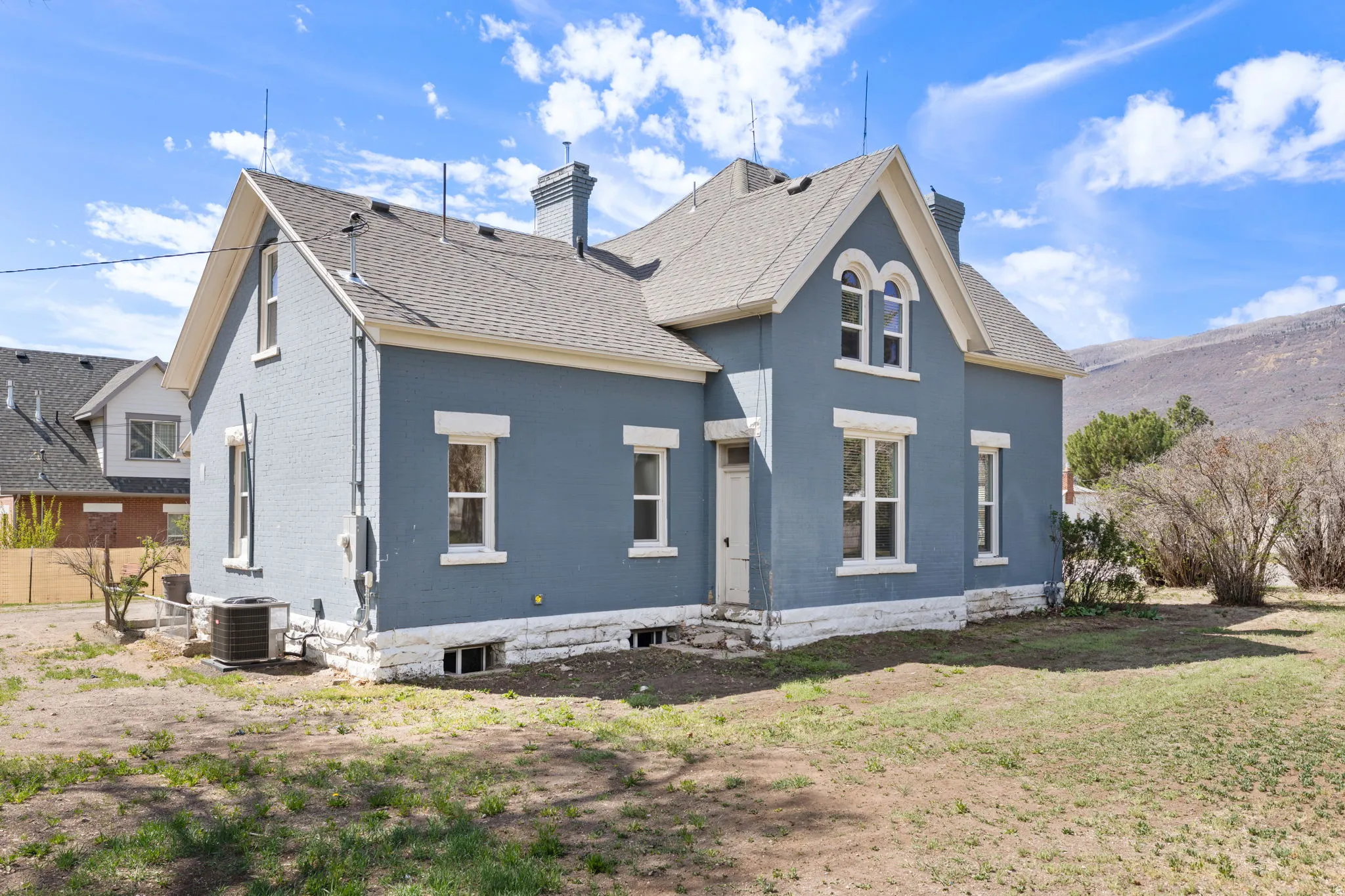 Rear view of property featuring a chimney, brick siding, and roof with shingles