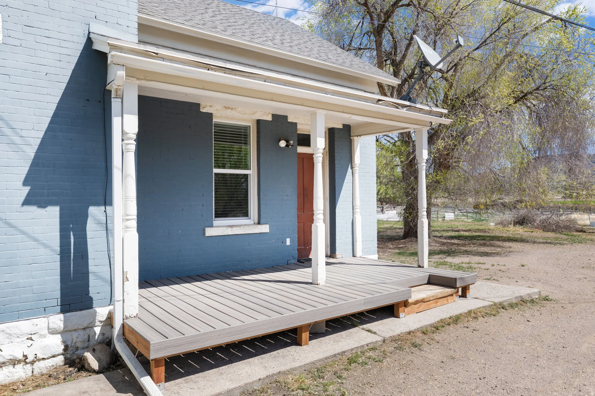 View of exterior entry with a porch, roof with shingles, and brick siding