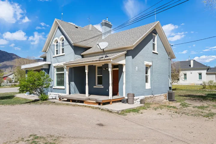 View of front of property with a porch, brick siding, a chimney, a mountain view, and a shingled roof