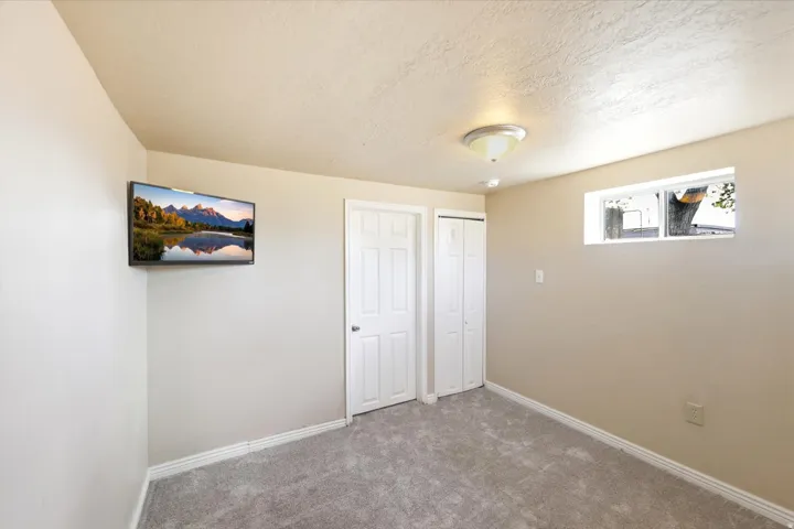 Room featuring light gray carpet flooring, neutral painted walls, white baseboards, and a single window