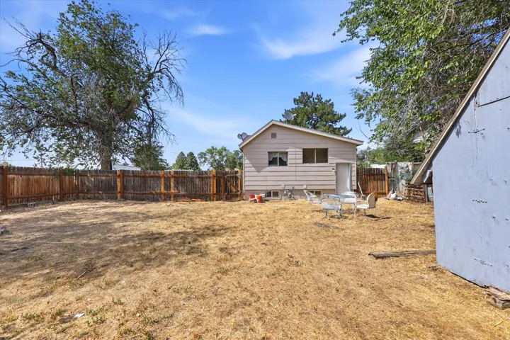 Spacious rear yard featuring a wood privacy fence, mature trees, and a detached storage shed