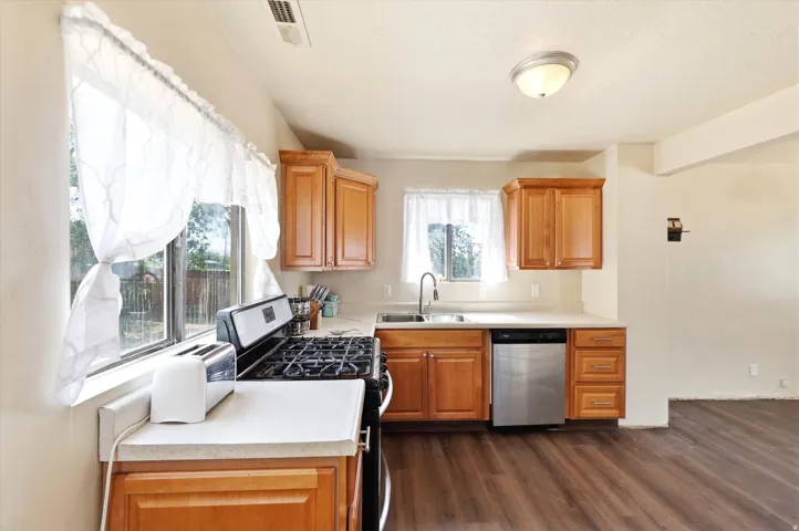 Kitchen featuring wood-finish flooring, light wood cabinetry, white countertops, and stainless steel appliances