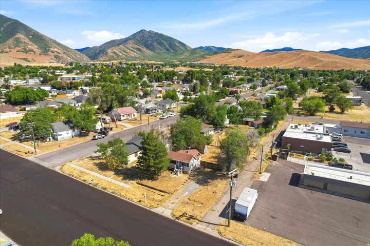 Aerial perspective showcasing an expansive residential area with mountain backdrop, established street grid, mature trees, and commercial structures