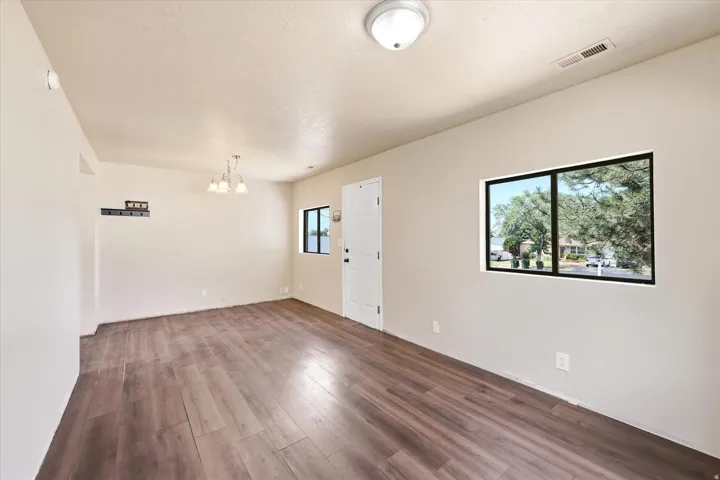 Expansive room featuring wood-finish flooring, neutral-toned walls, and a contemporary ceiling light fixture