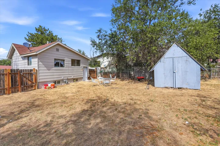 Expansive backyard featuring a detached storage shed, wood fence, and mature trees