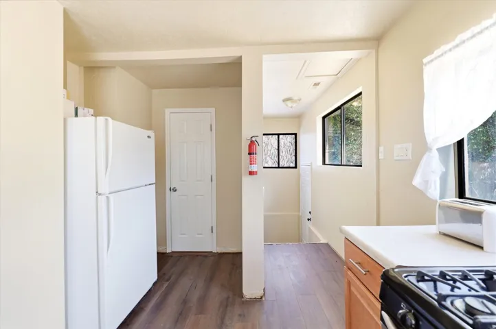 Kitchen area featuring wood-finish flooring, light-toned walls, and a window with white drapes