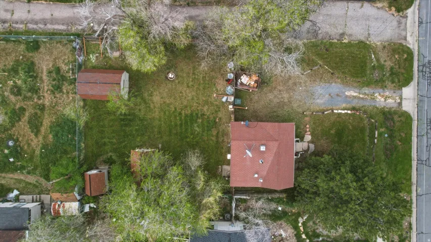 Expansive lot featuring a single-story residence with a red shingle roof, two outbuildings, and mature trees