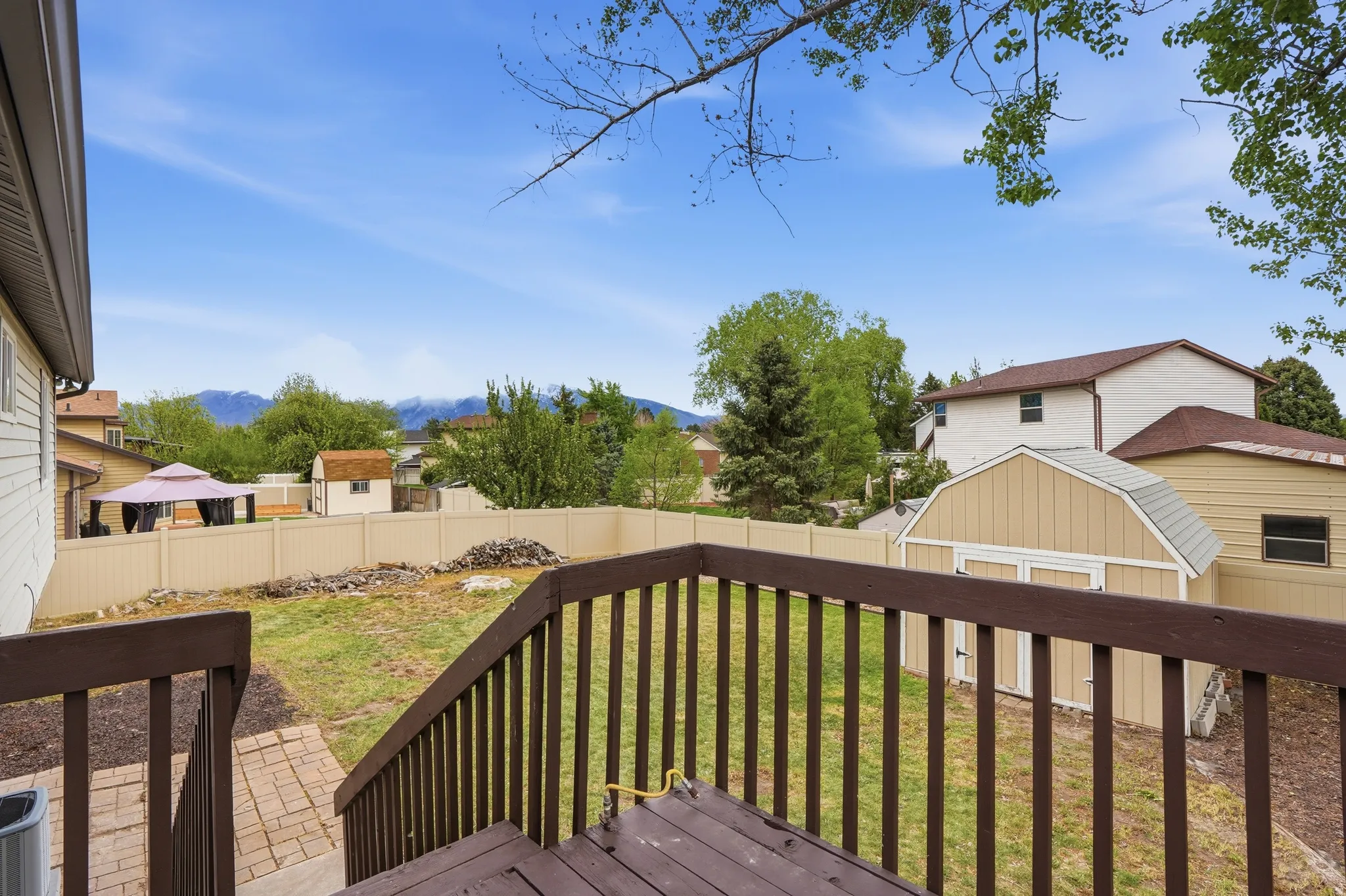 Wooden terrace with a fenced backyard, a storage shed, a residential view, and a mountain view