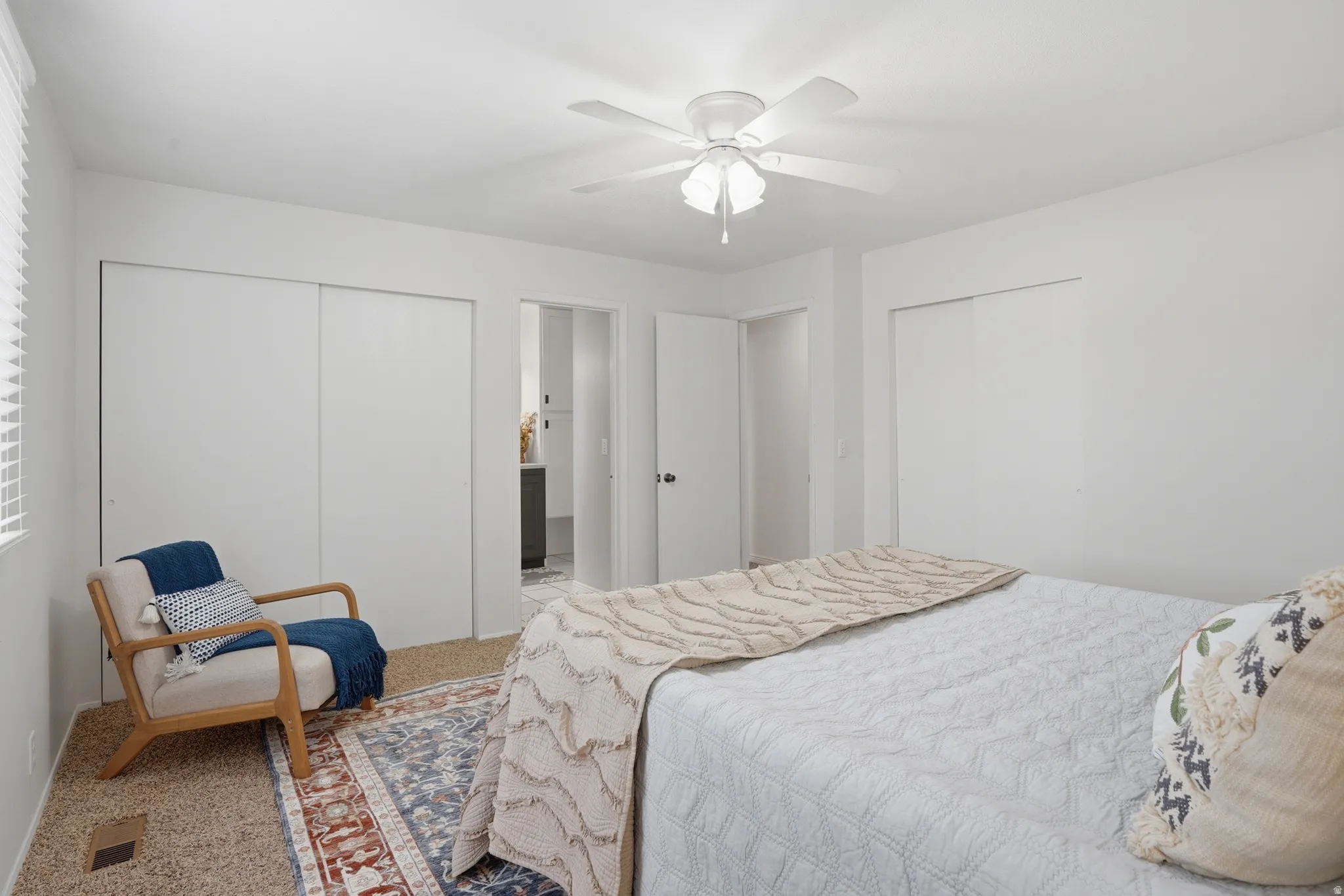 Carpeted bedroom with two closets and ceiling fan