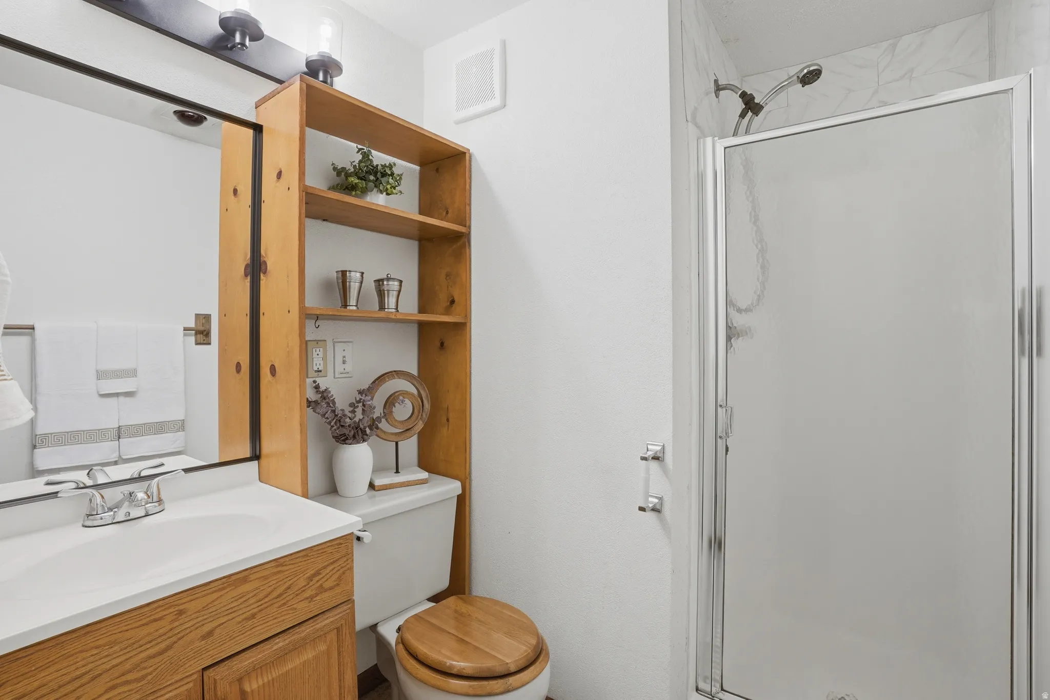Full bath featuring a shower stall and vanity