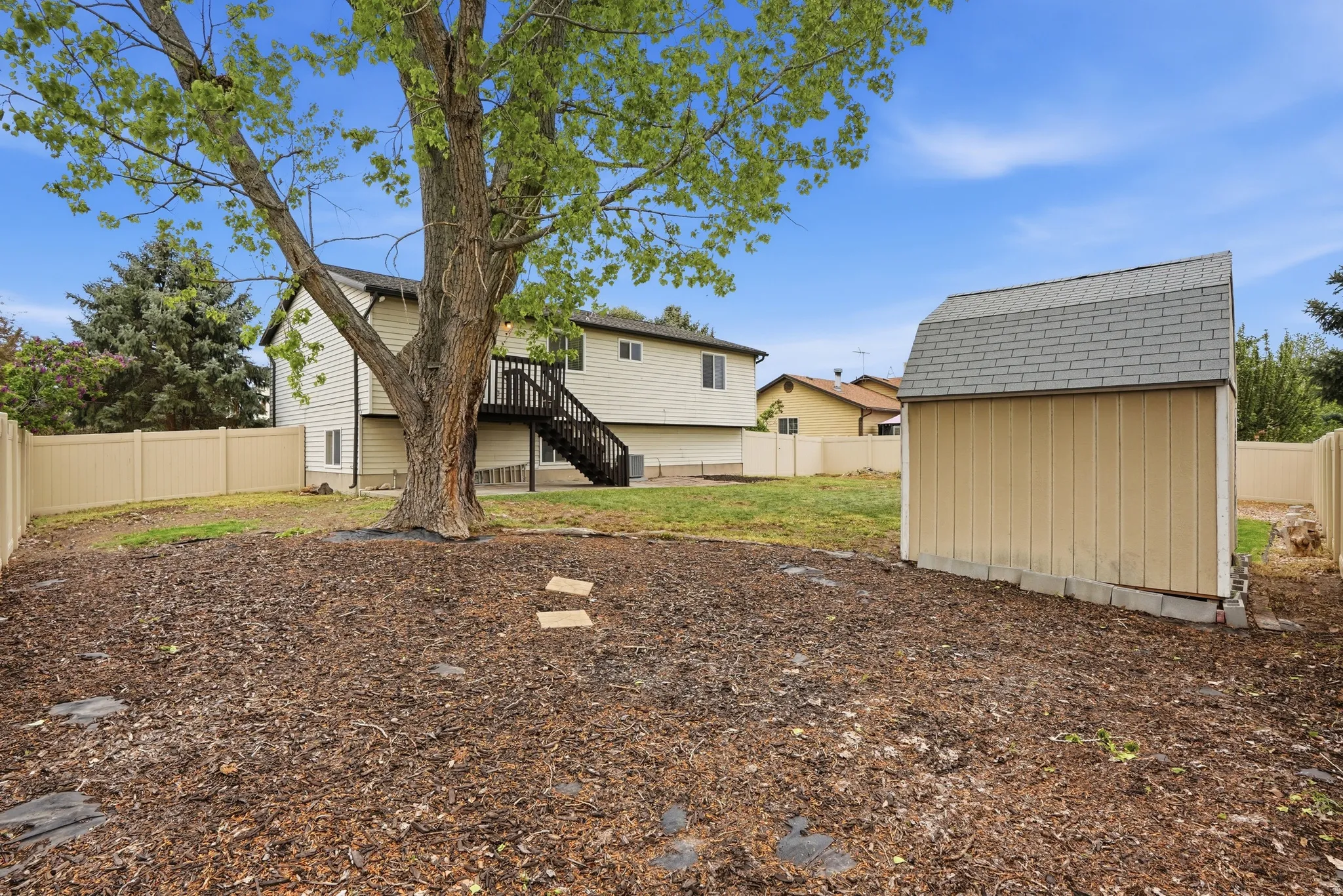 Back of house with a fenced backyard, a storage unit, and a deck