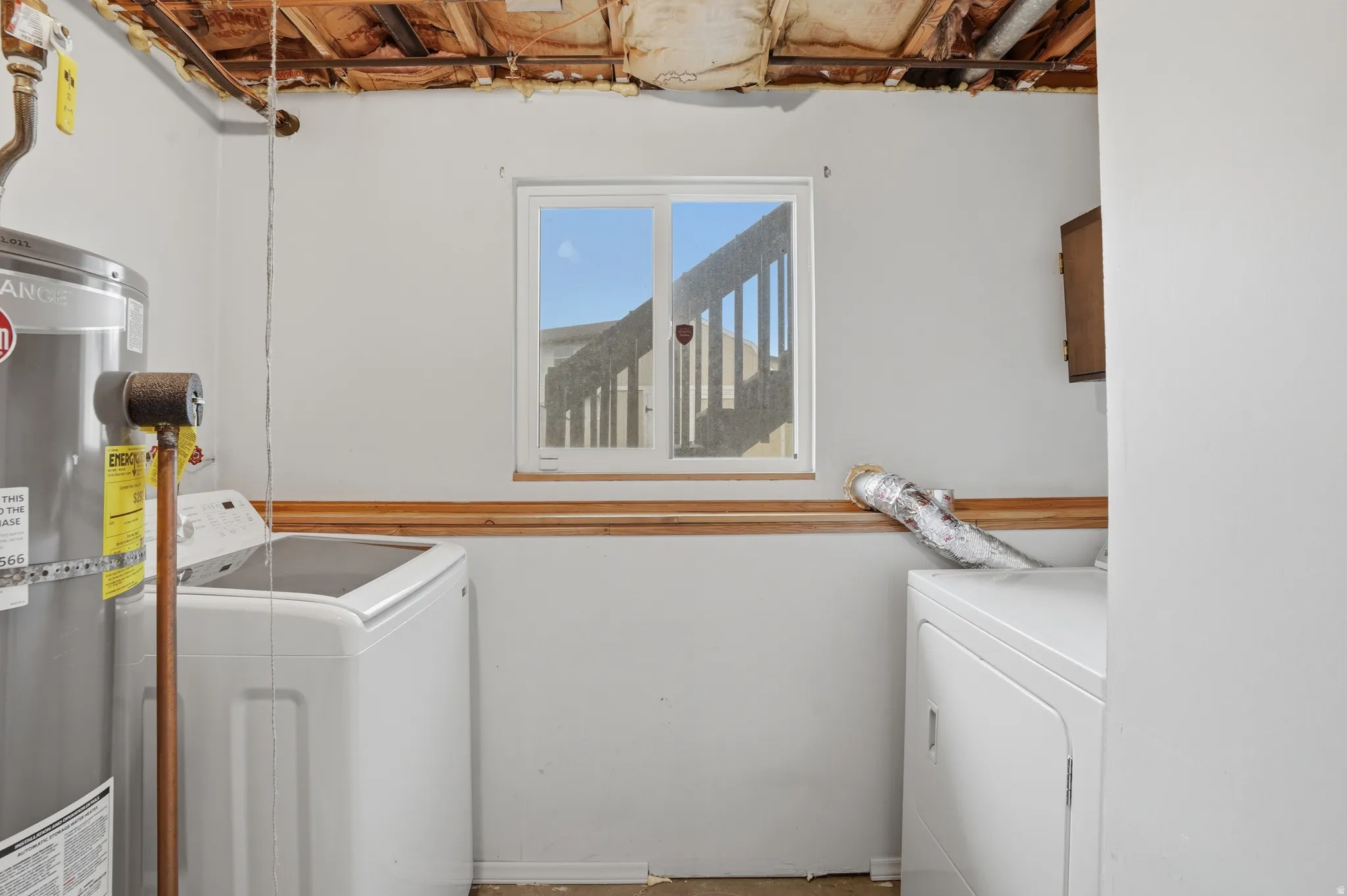 Laundry area featuring washing machine and clothes dryer and strapped water heater