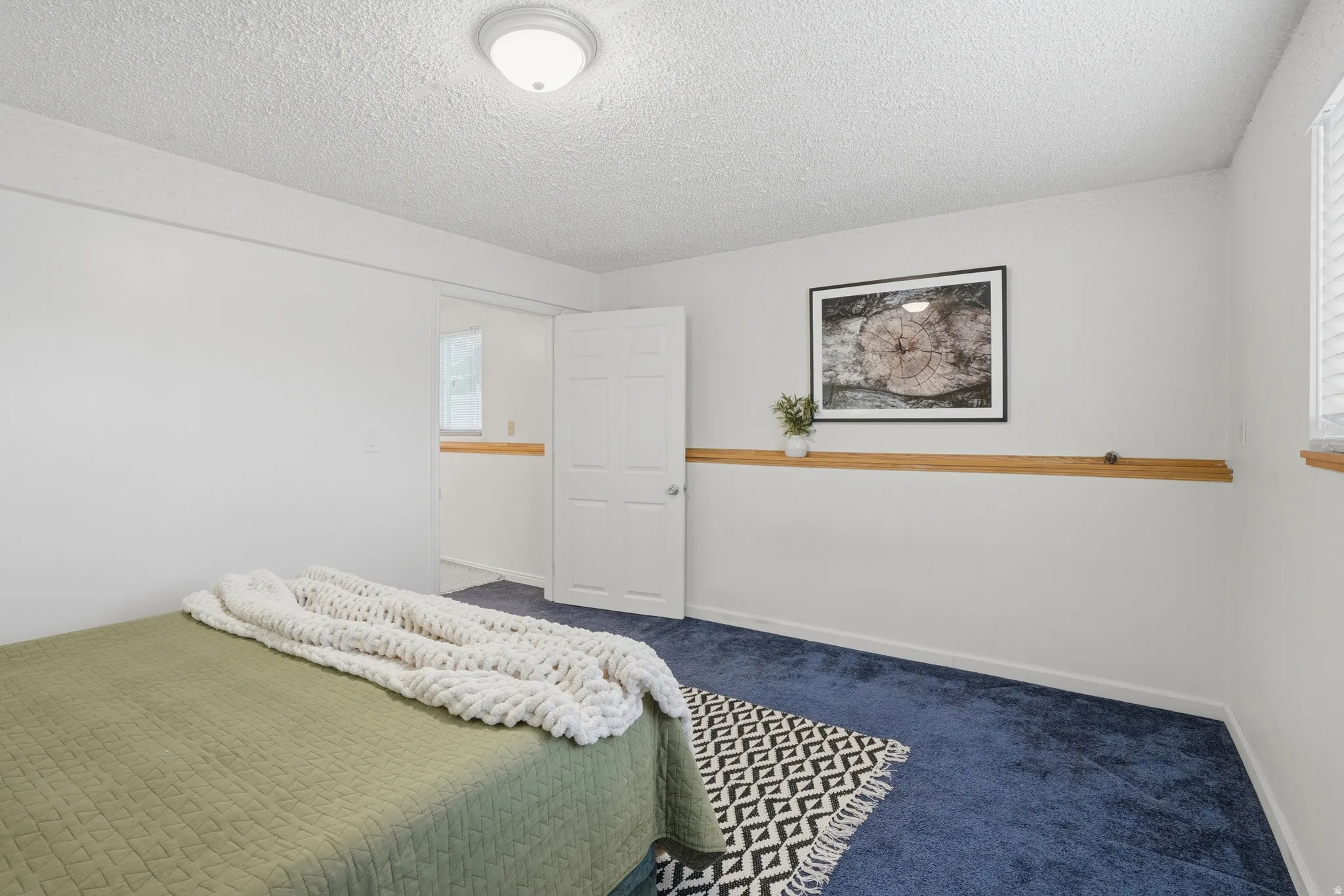 Carpeted bedroom featuring a textured ceiling and baseboards