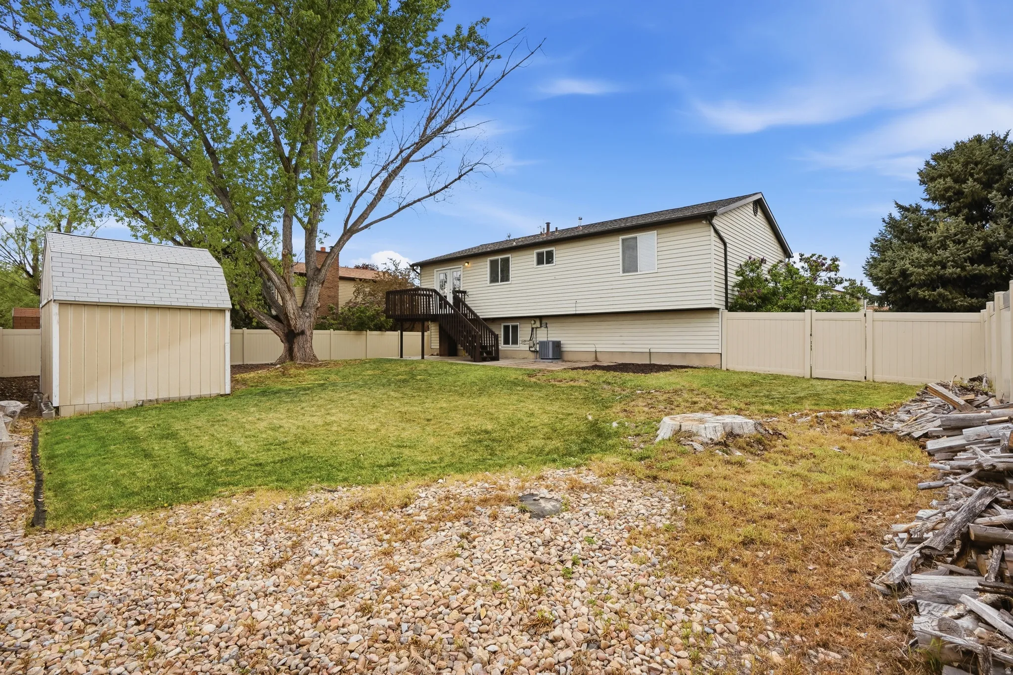 Back of property with a fenced backyard, a deck, and a storage shed