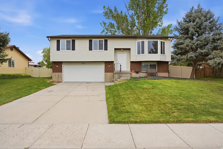 Bi-level home with brick siding, concrete driveway, a garage, and a gate