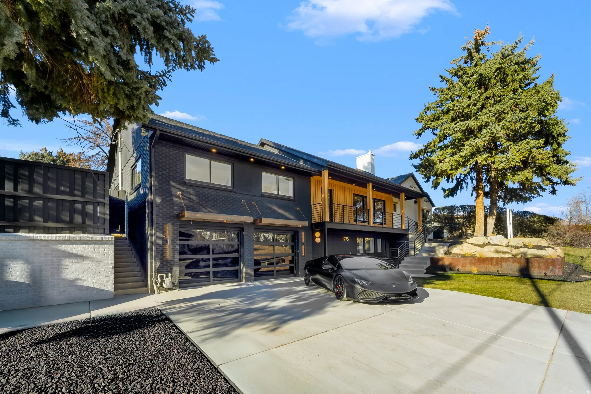 View of front of property with brick siding, driveway, a chimney, a garage, and a balcony