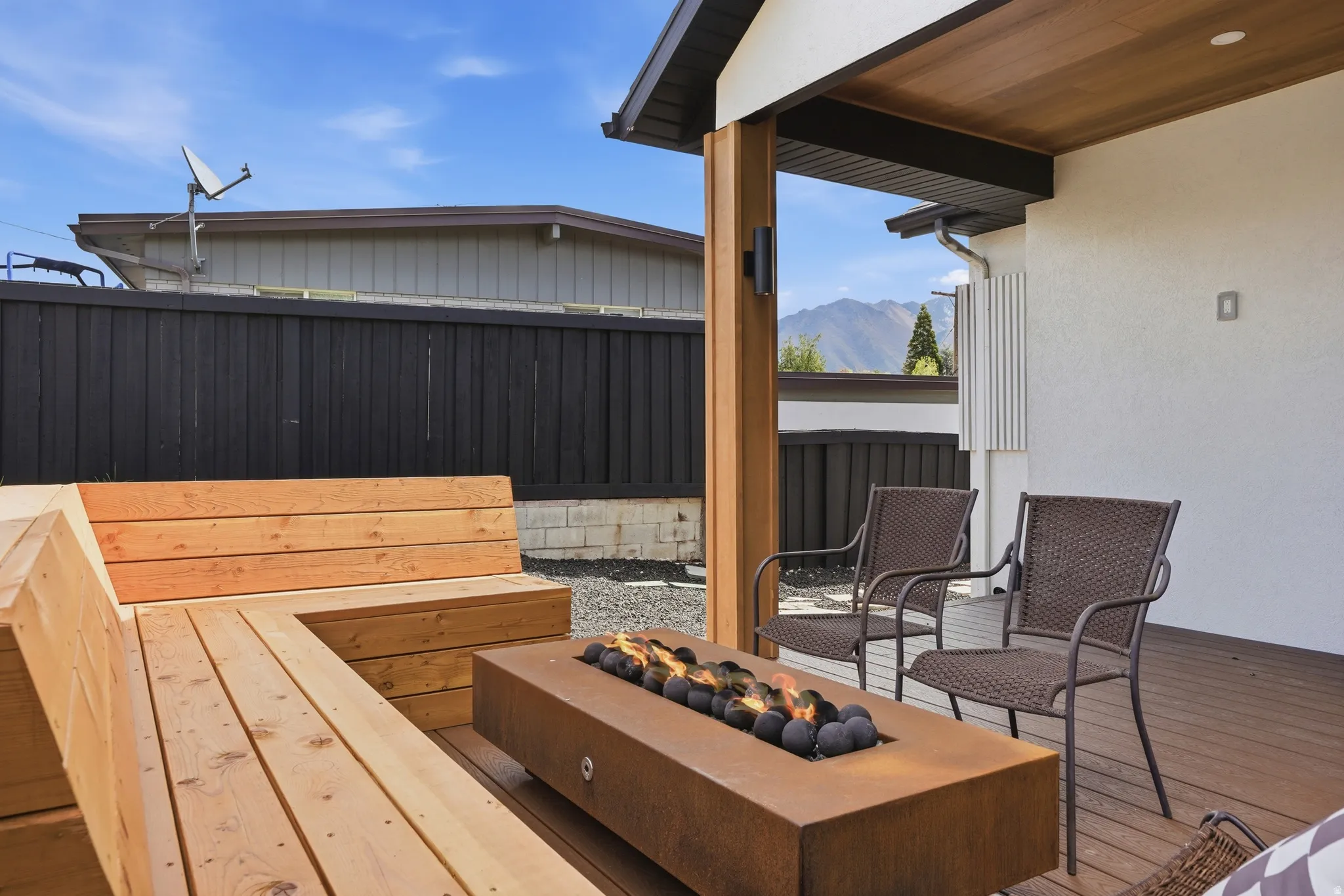 Wooden terrace with a fire pit, a fenced backyard, and a mountain view