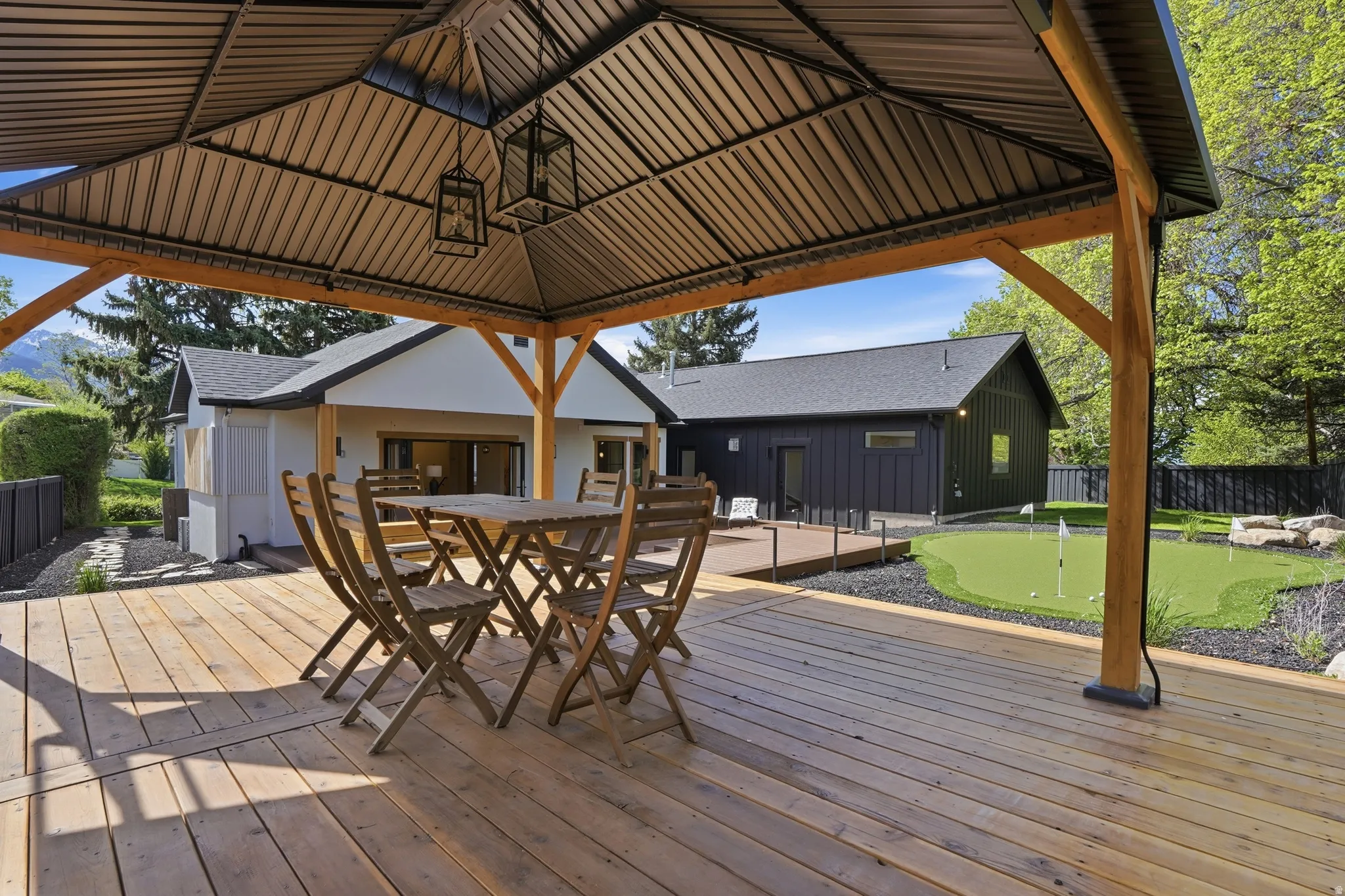 Wooden deck with a putting area, outdoor dining area, a gazebo, and a patio area