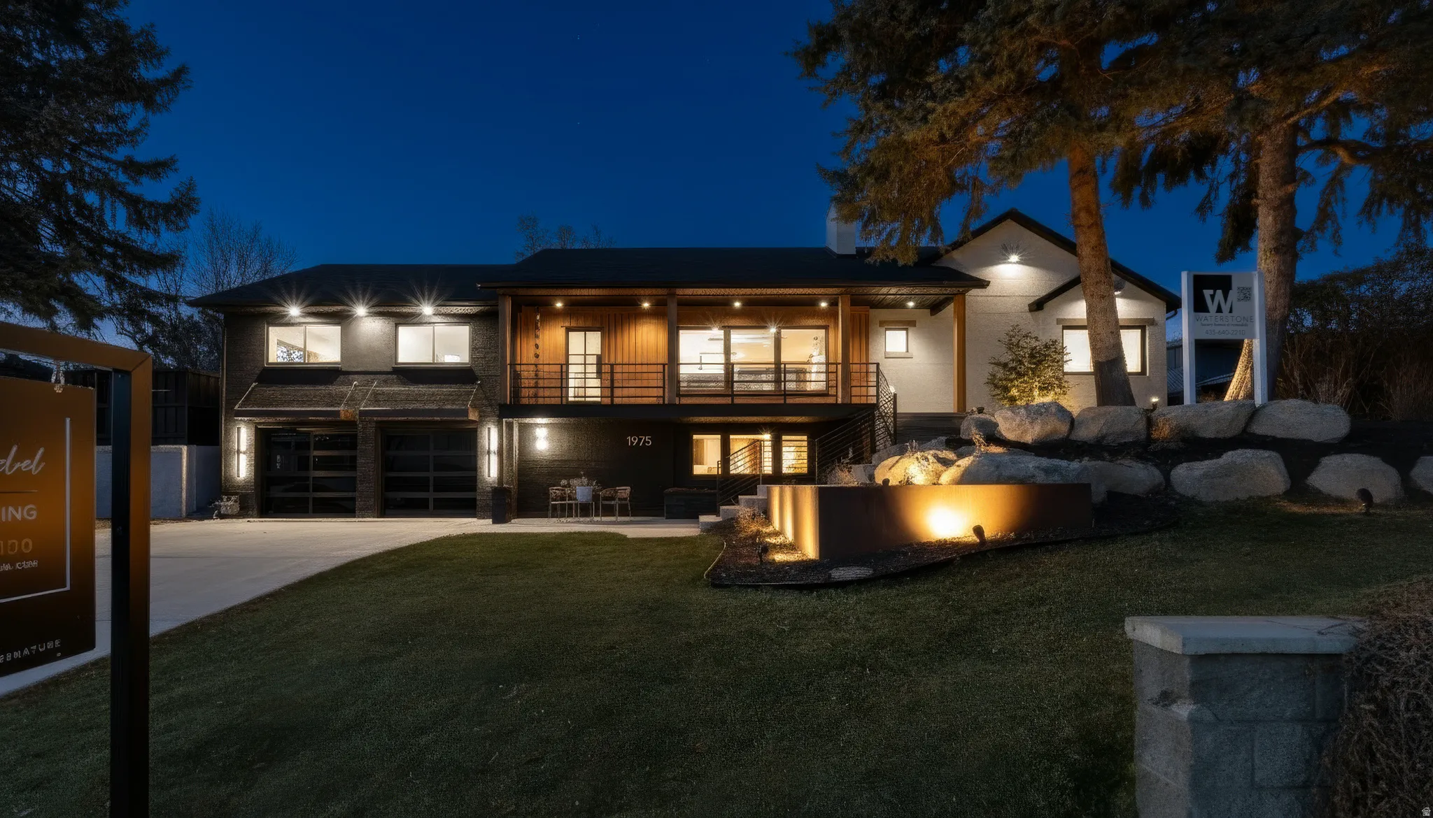 Back of house at twilight with concrete driveway, a garage, a lawn, and a balcony