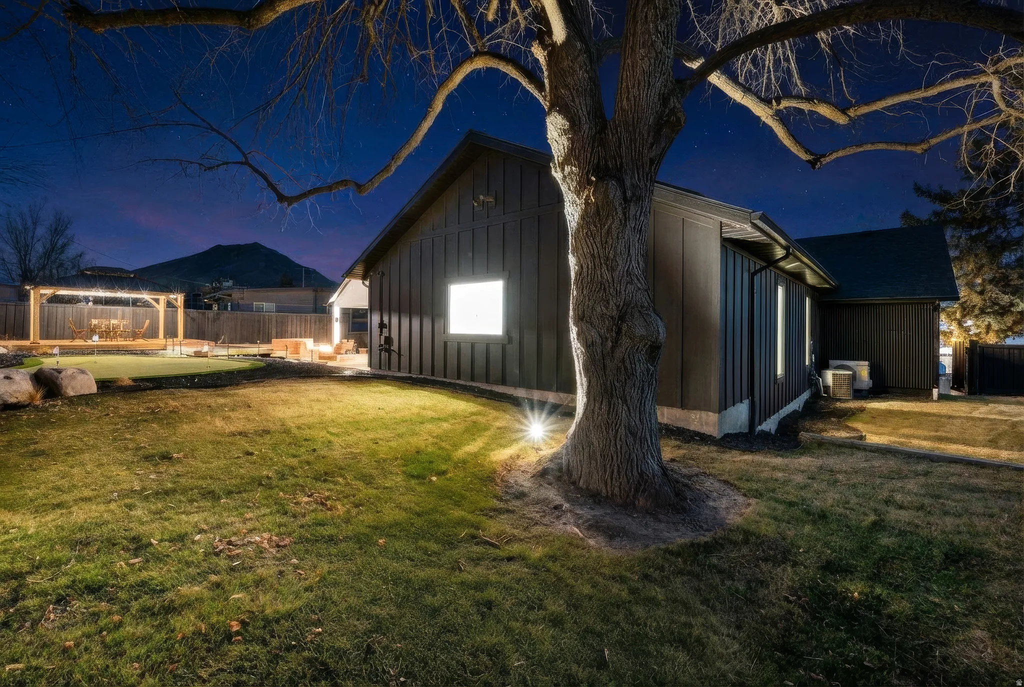 Property exterior at twilight with board and batten siding and a putting area