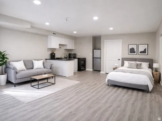 Bedroom with freestanding refrigerator, recessed lighting, and light wood-type flooring
