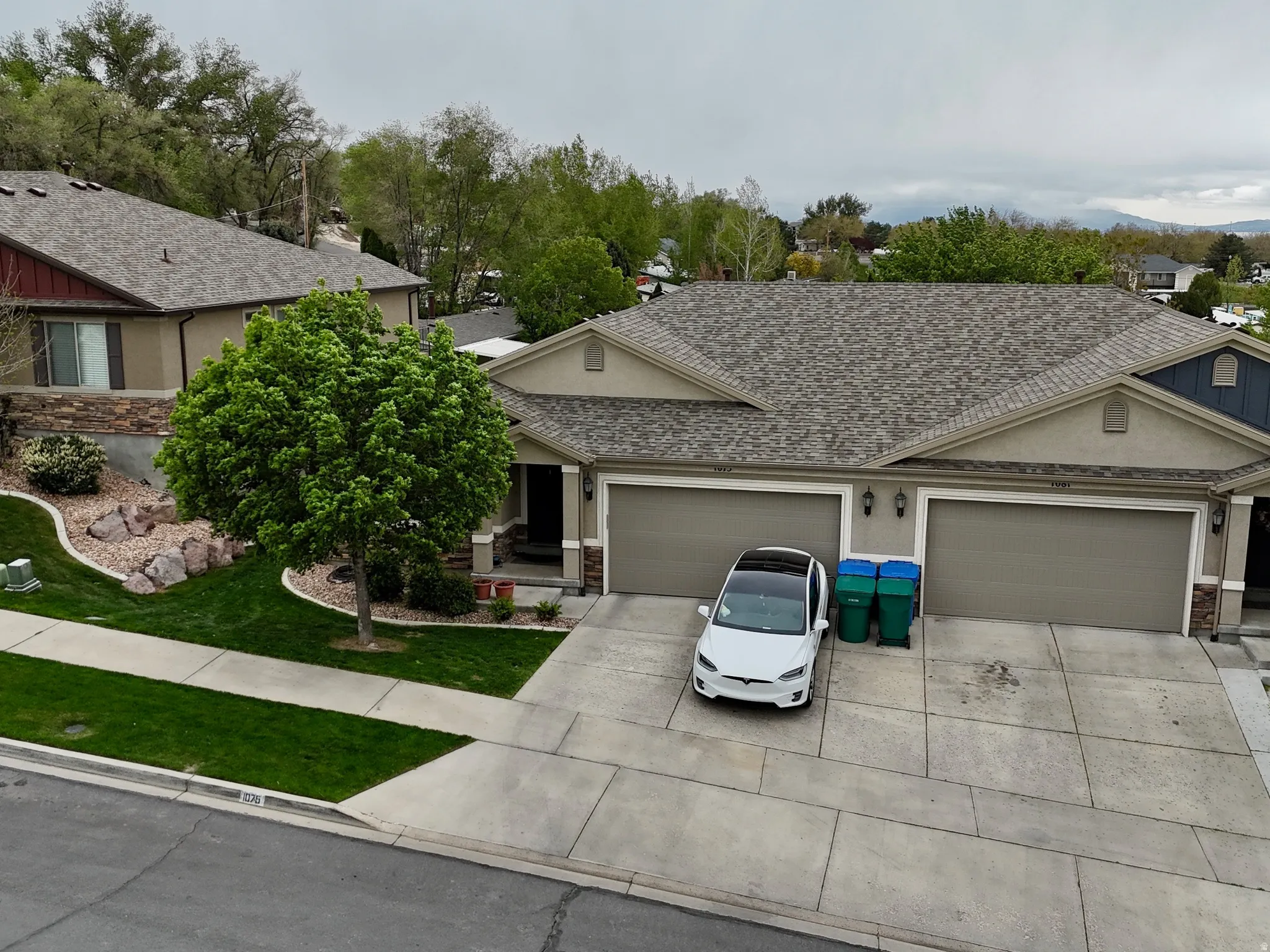 View of front facade featuring concrete driveway, a garage, stone siding, and a front lawn