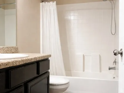 Bathroom featuring vanity, shower / tub combo with curtain, and stone finish flooring