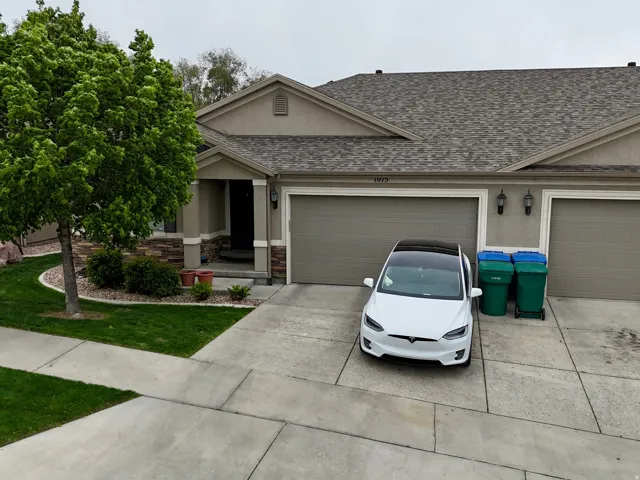 View of front of property with roof with shingles, driveway, stucco siding, and a front lawn