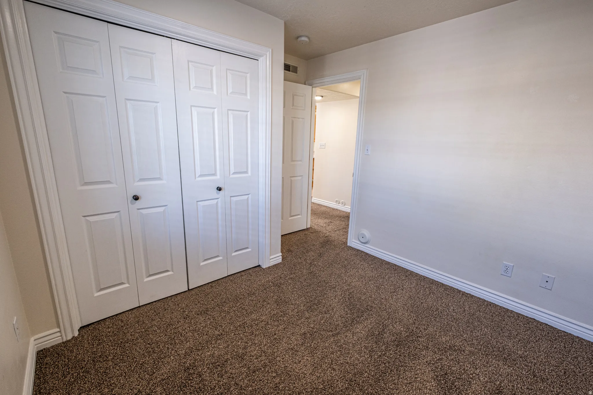 Unfurnished bedroom with dark carpet and a closet