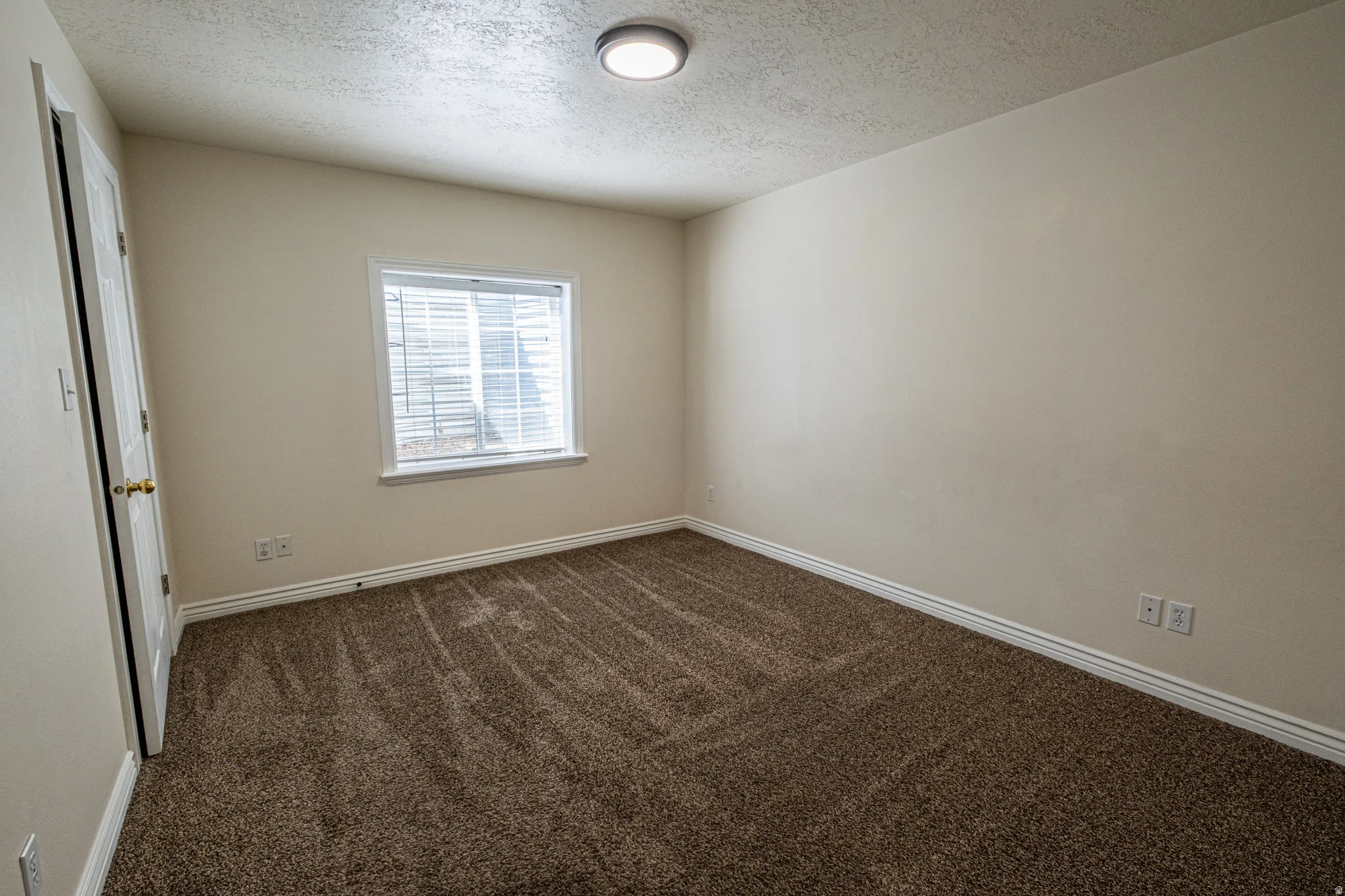 Unfurnished room featuring dark colored carpet and a textured ceiling