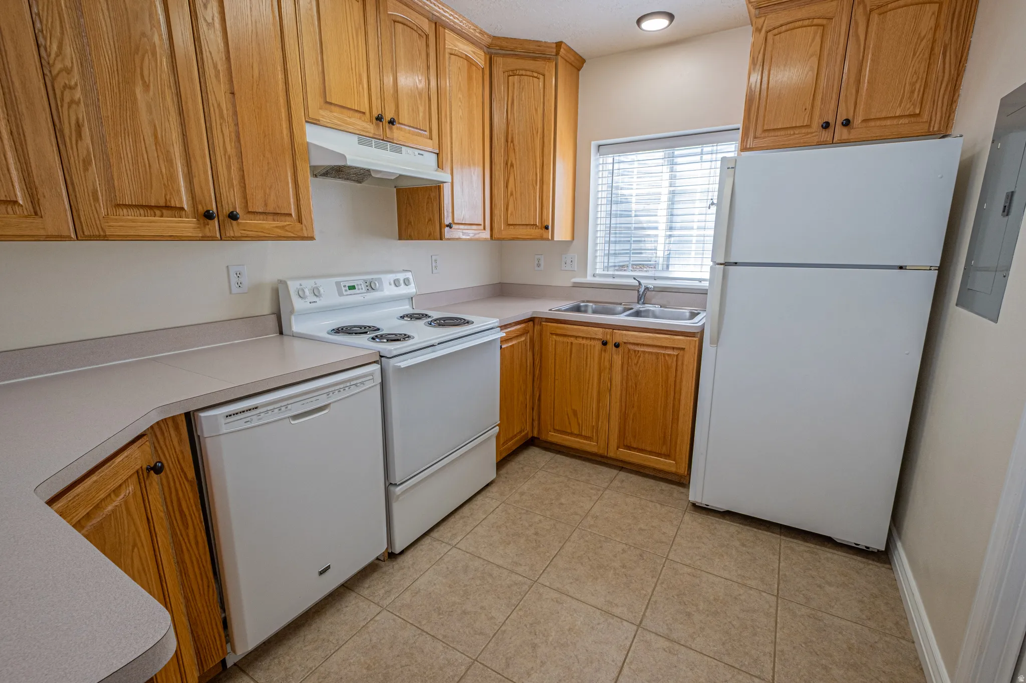 Kitchen with white appliances, light countertops, and wood finish cabinetry