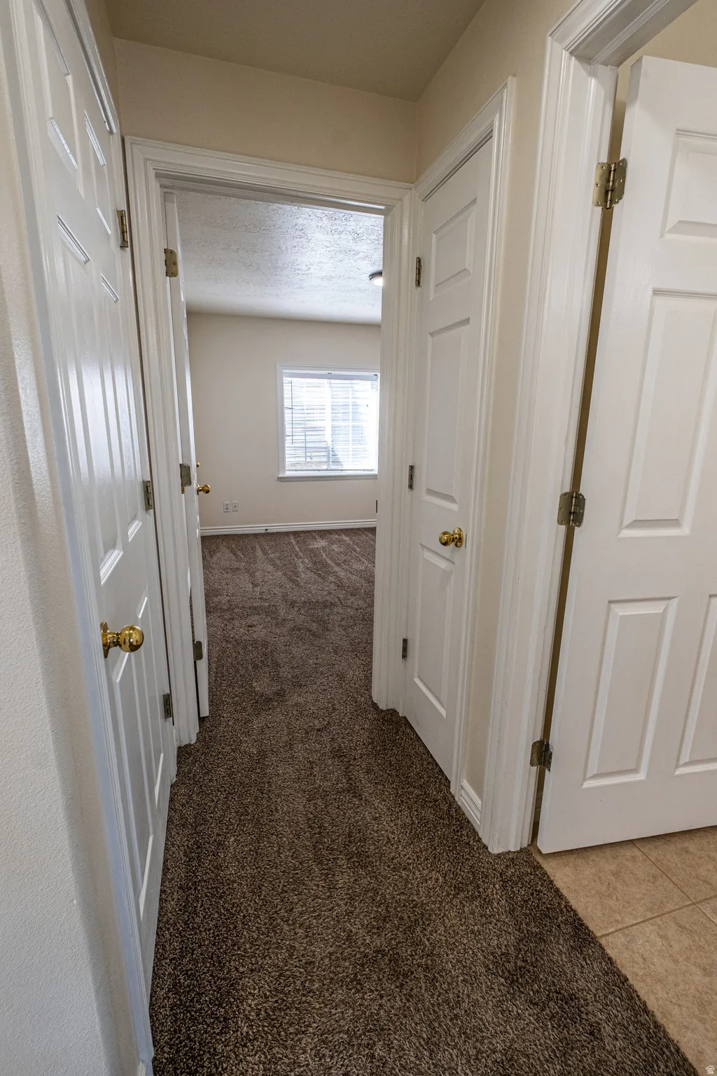 Corridor with light colored carpet and a textured ceiling